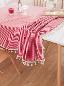 Detailed close-up of red and white striped tablecloth with cream cotton tassels