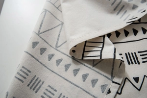 Close-up detail of bohemian linen fabric with black geometric patterns and fine stitching