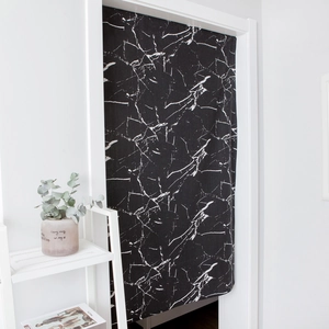 Modern black marble print door curtain in a minimalist interior setting with green plants