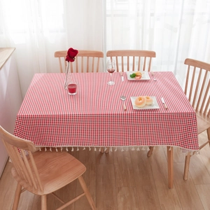 Pastoral red and white checkered tablecloth with fringe on a wooden table