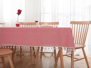 Close-up of red and white checkered tablecloth featuring delicate off-white fringe tassels