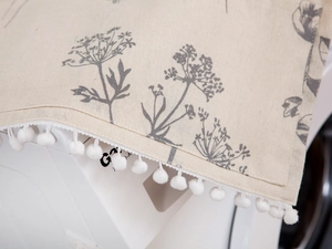 Detail of linen fabric appliance cover with grey floral print and white pom-pom trim