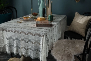 Close-up of vintage white lace tablecloth with scalloped edges and floral hollow patterns