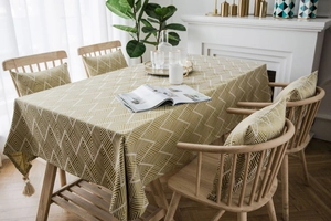 Detail of olive green herringbone tablecloth featuring decorative tassel pendant edges
