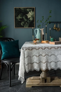 Detail of vintage white lace tablecloth featuring scalloped edges and floral crochet patterns