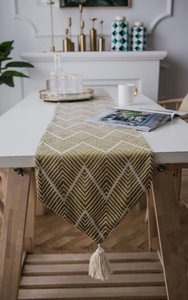 Detail of olive green chevron table runner with handmade tassels for Nordic home decor