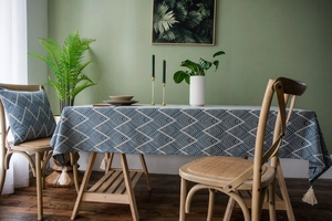 Close-up of navy jacquard tablecloth with geometric patterns and beige tassels in a home setting