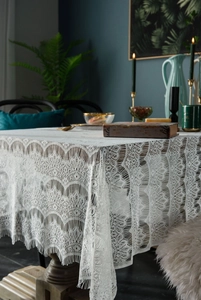Macro detail of white floral lace tablecloth featuring elegant scalloped edges and texture