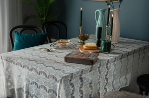 Detailed view of white hollow lace tablecloth with elegant scalloped edges in a warm setting