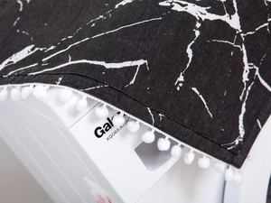 Detail der schwarzen Marmordruck Kühlschrankabdeckung mit eleganten weißen Pompon-Rändern