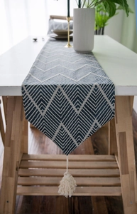 Detail of blue and white zigzag table runner with woven cotton texture and handmade tassels