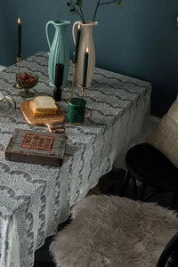Detail of white eyelash lace tablecloth featuring intricate floral embroidery and scalloped edges