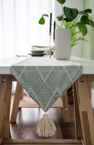 Detailed view of sage green Nordic table runner with geometric weave and tassels