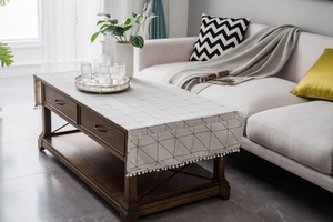 Detail of minimalist cotton linen table runner with geometric patterns and white pom pom fringe
