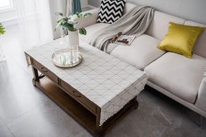 Close-up of beige cotton linen tablecloth with black grid pattern and white tassels