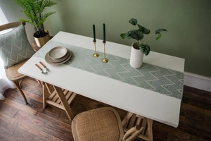Detail of Nordic jacquard table runner featuring green geometric weave and tassels