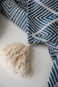 Detail of navy blue geometric pattern tablecloth with decorative white cotton tassels