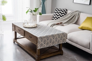 Detail of linen table runner with blue vintage floral pattern and white pom-pom fringe