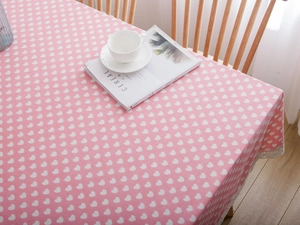Detail of pink cotton linen tablecloth with white heart patterns and delicate lace edges