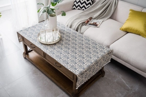 Close-up of cotton linen tablecloth with blue floral patterns and white tassel fringe