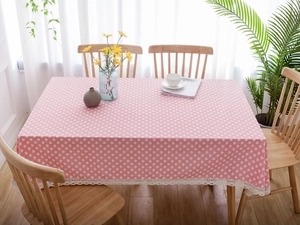 Detailed close-up of pink linen tablecloth with white heart patterns and lace borders