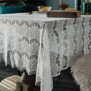 White vintage lace tablecloth with hollow embroidery and delicate fringe on a wooden table