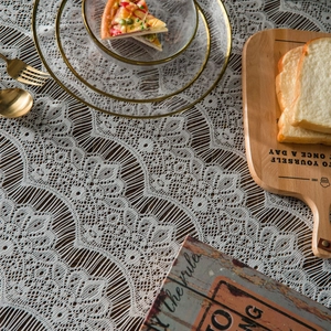 White floral lace tablecloth with hollow embroidery on dark wooden table for dining