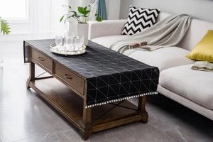 Detail of modern black cotton linen table runner with white geometric grid and pom-poms