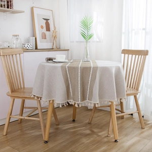 Detail of round cotton linen tablecloth featuring striped design and beige fringe tassels