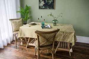 Detail of yellow geometric tablecloth with white cotton tassels on a wooden table