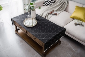 Detailed view of black geometric tablecloth with white pom-pom fringe and linen texture