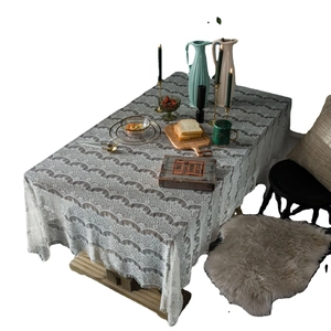 White lace tablecloth with crochet hollow pattern and tassel edges on wooden table