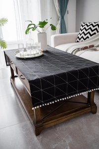 Close-up of black cotton linen table runner with white geometric patterns and small tassels