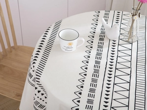 Detail shot of boho geometric black and white linen tablecloth on a round wooden dining table