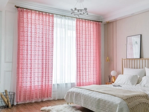 Detailed close-up of pink crochet lace curtains with hollow diamond patterns and tassel trim