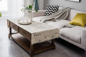 Detail of linen table runner with vintage floral patterns and white pom-pom fringe trim