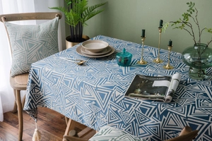 Detail of blue and beige geometric linen tablecloth with decorative fringes and tassels