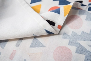 Detailed close-up of geometric printed linen tablecloth with neat edge stitching and fabric texture