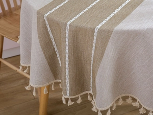 Close-up of linen table cloth with beige brown stripes, geometric embroidery and tassels