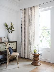 Detail of bohemian cotton linen curtain featuring black geometric prints and fringe trim