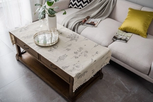 Close-up of linen table runner with floral patterns and white pom-poms on wood table