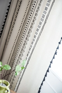 Detailed close-up of Bohemian cotton linen curtain with black tribal prints and tassels