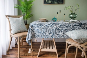 Close-up of geometric blue and white tablecloth with white fringe tassels and matching pillows