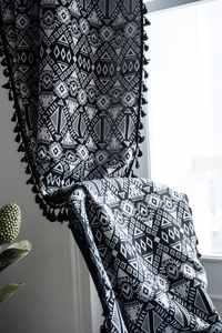 Close-up of geometric jacquard pattern and black tassel trim on boho cotton linen curtains