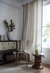 Detail of bohemian cotton linen curtain with black geometric prints and tassel trim