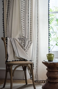 Detail of bohemian cotton linen curtain with black geometric prints and tassel edges