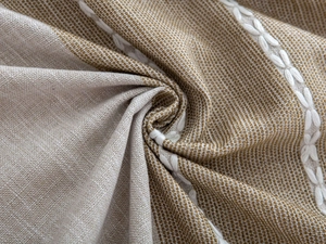 Detailed close-up of linen table cloth with white leaf embroidery and rustic texture