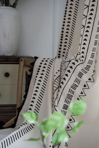 Detail of bohemian black and white geometric print on cotton linen fabric with tassels