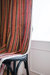 Detail view of Bohemian striped linen curtain with intricate geometric patterns and lace edge