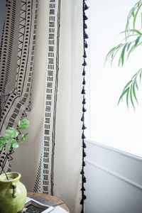 Detail of bohemian cotton linen curtain with black geometric patterns and tassels